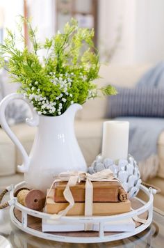 a white vase filled with flowers sitting on top of a table next to a book