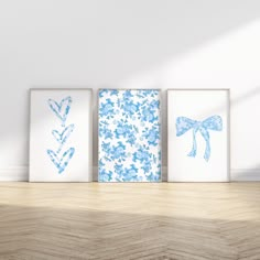 three blue and white prints are on the wall next to a wooden floor in an empty room