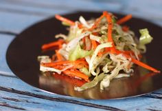 a black plate topped with coleslaw and carrots