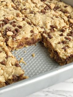 chocolate chip oatmeal cookie bars cut in half on a baking pan with one slice missing