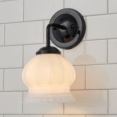 a light that is on the side of a white brick wall in a bathroom area