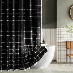 a black and white shower curtain hanging in a bathroom next to a sink with a mirror on the wall