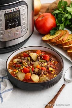 a bowl of soup next to an instant pot with bread, tomatoes and parsley