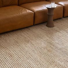 a brown leather couch sitting on top of a carpeted floor