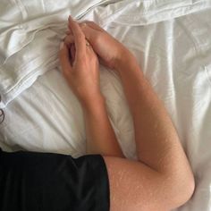 a person laying in bed with their hands on top of each other's pillow