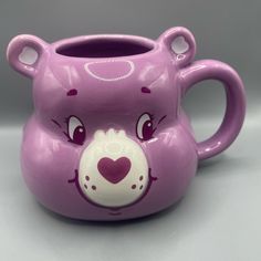 a purple bear shaped vase with a heart on it's face and eyes painted on the side