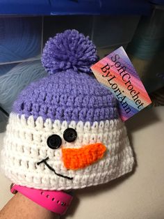 a purple and white knitted snowman hat with a tag on it's ear