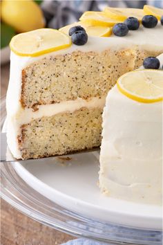 there is a cake with lemons and blueberries on the top it has one slice cut out