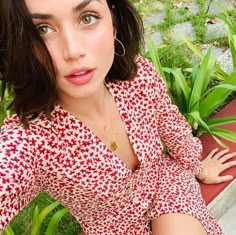 a woman in a red and white dress sitting on a bench with her arms crossed