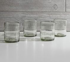 four glasses sitting on top of a table next to each other, one filled with water