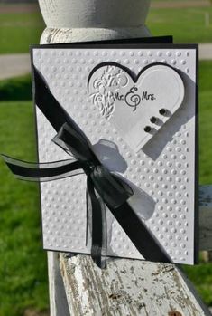 a white card with a black ribbon attached to it and a heart in the middle