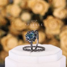 a ring is sitting on top of a white box with roses in the back ground