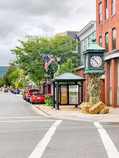 a clock on the side of a building next to a street with cars parked in front