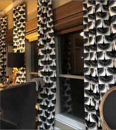 two black and white curtains hanging from the side of a window next to a chair