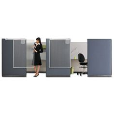 a woman is standing in an office cubicle with three partitions and one chair