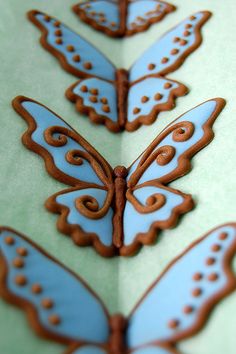 the cookies are decorated with blue and brown icing on top of each other's wings