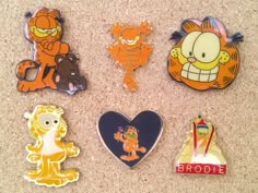 six pin badges with cartoon characters on them sitting on the floor next to each other