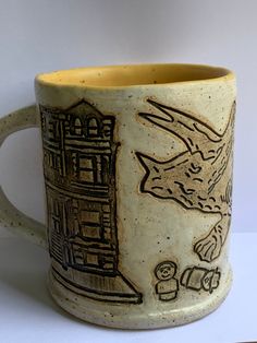 a ceramic mug with an image of a building and a bird on the outside, in front of a white background