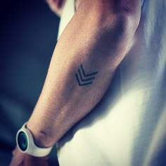 a man's arm with a small arrow tattoo on the left side of his arm