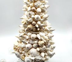 a christmas tree made out of seashells on a white surface with ornaments around it