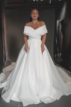 a woman wearing a white wedding dress standing in front of a black and white backdrop