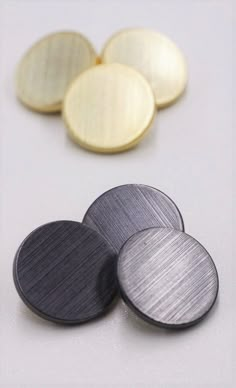 four metal discs sitting on top of a white table next to each other and one is empty