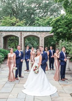 a bride and groom with their bridal party in front of an archway at the park