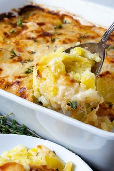 a white casserole dish filled with potatoes and topped with a serving spoon full of mashed potatoes