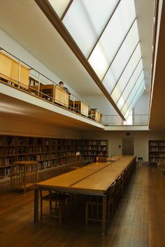 an empty library with tables and bookshelves in the middle, on hard wood flooring