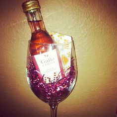 a wine glass filled with purple confetti and a bottle of gatlo