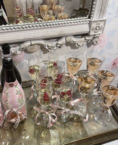 a table topped with lots of glasses filled with champagne next to a bottle of wine