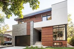 a modern house with wood siding and glass windows on the front door is seen in this image