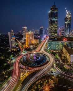 an aerial view of a city at night with many lights and buildings in the background