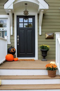 a front porch decorated for halloween with pumpkins and gourds on the steps