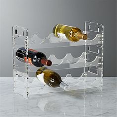 three bottles of wine are sitting on a clear shelf with two empty ones in it