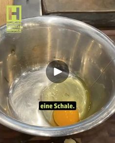 an egg is in a metal bowl on a table with other food items and words