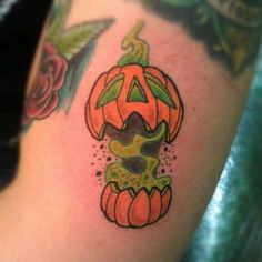 a close up of a person's arm with a tattoo on it and a pumpkin