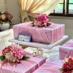 there are many pink wrapped gifts on the trays with flowers and ribbons around them