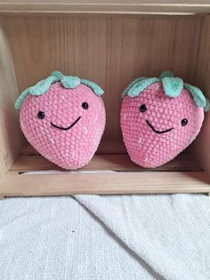 two stuffed strawberrys sitting in a wooden box