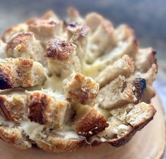 bread with cheese and meat in it on top of a wooden plate, ready to be eaten