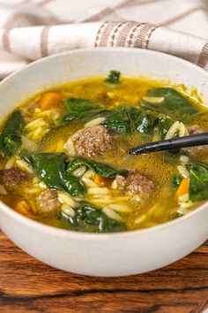 a white bowl filled with meat and vegetable soup on top of a wooden cutting board