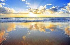 the sun is setting over the ocean with clouds in the sky and sand on the beach