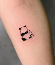 a small panda bear tattoo on the arm