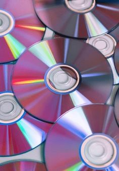 several cd's are stacked on top of each other with different colored discs in the middle