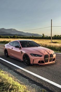 an orange sports car is driving down the road with mountains in the backgroud