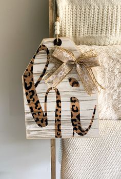 a wooden sign with a leopard print bow hanging from it's side on a chair