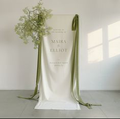 a white chair with a green ribbon tied around it and a bouquet of flowers in the back