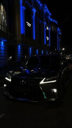 a black car parked in front of a building at night with blue lights on it