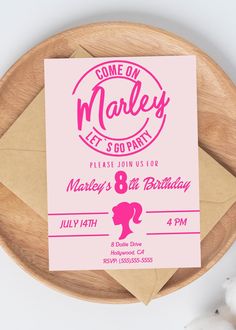 a pink birthday party card sitting on top of a wooden plate