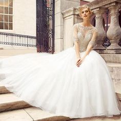 a woman in a white wedding dress sitting on the steps with her hand on her hip